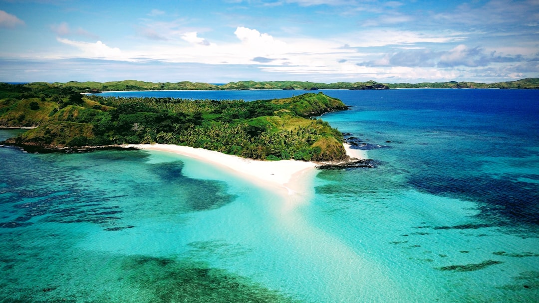 Turquoise Fiji water beside a green island and pale beach